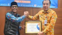 Pj Bupati Merangin H Mukti saat menerima penghargaan dari Ombudsman RI Perwakilan Provinsi Jambi, Saiful Roswandi.